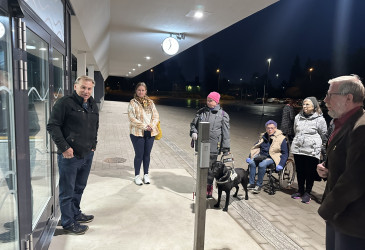 Ihmisiä seisomassa aseman ulko-ovella.