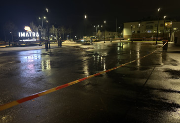 Aukio sataisella ja pimeällä säällä. Aukio on rajattu varoitusnauhalla, taustalla näkyy Imatra-valokyltti.