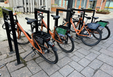 Oranssit kaupunkipyörät telineissä.