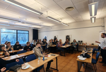 Ihmisiä luentosalissa kuuntelemassa luennoitsijaa.