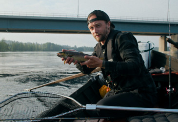 Kalastajalla kala kädessään veneessä.