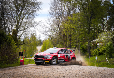 Punainen ralliauto ajamassa tiellä.