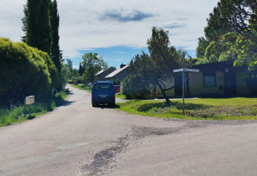 Kuvassa asuinkadun risteyksessä sininen pakettiauto kesällä.