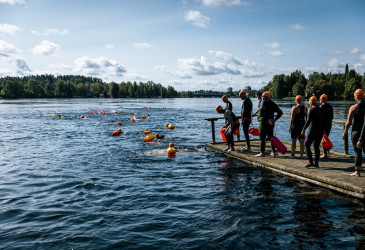 Uimareita märkäpuvuissa Vuoksessa ja laiturilla.