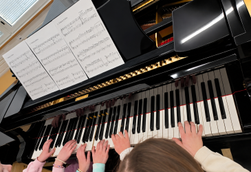 Kolme lasta soittaa pianoa.