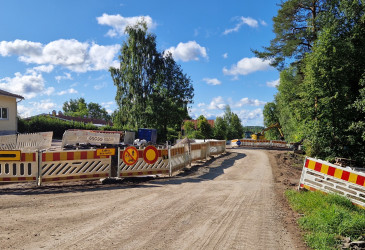Sorapintaisen tien reunoilla työmaa-aitoja ja liikennemerkkejä.