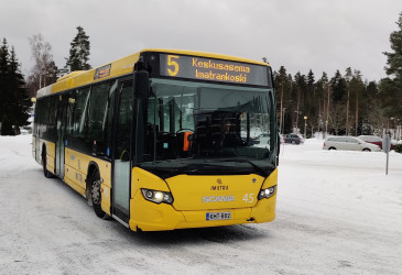 linja-auto edestä, taustalla parkkipaikka ja kuusia.