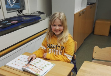 Emmi Liiri istumassa pulpetilla kirja edessään.