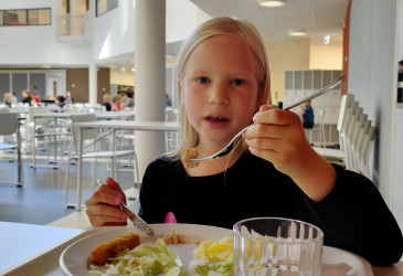 Husu syömässä kalapuikkoja Vuoksenniskan koulun ruokalassa.