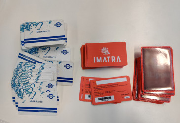 Pinoissa vanhoja ja uusia matkakortteja sekä heijastavia koteloita.