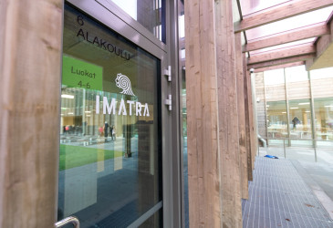 Koulun lasinen ulkoseinä, puuta ja Imatra-logo