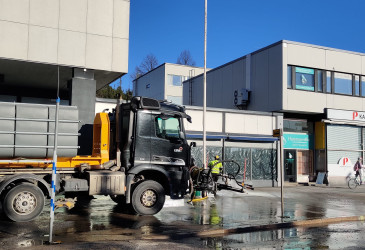 Kuorma-auto ja kadun pesijä ruiskun kanssa, taustana kerrostaloja.