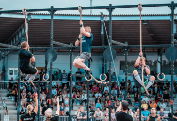 CrossFit kilpailu. Osallistujat kiipeävät köyttä pitkin ylös. Yleisöä taustalla.