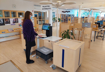 Nainen käyttää kirjaston lainaus-palautusautomaattia.