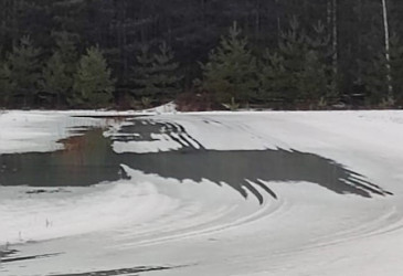 latu, jolta lumi osittain sulanut ja vettä ladulla, taustalla kuusikko.