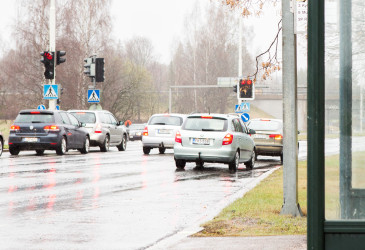 Autoja liikennevaloissa, etualalla bussipysäkki.