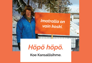 Mies kosken ääreellä kyltin kanssa.