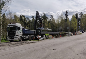 Kuorma-auto ja työmiehiä kaivuutöissä ajotien reunassa.