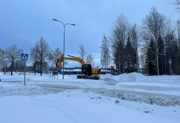 Kaivinkone mataloittaa risteyksen lumivalleja.