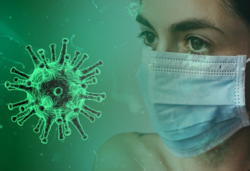 Nainen maskissa, koronavirus kuvitettuna vieressä