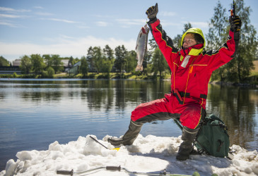 Mies muka nappaamansa kalan kanssa kesäisellä vuoksella jäälautalla