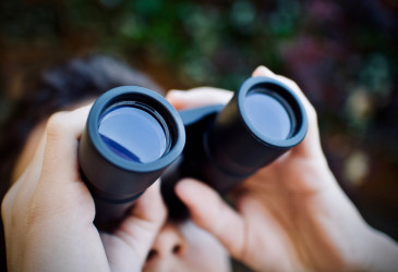 Nainen katsoo kiikarila taivaalle