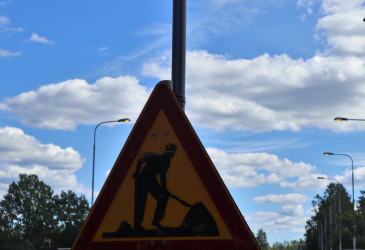 Tietyömerkki, jonka taustalla on taivas ja katuvalaisimia.