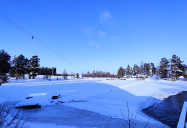 Talvinen kuva Vuokselta. Kuvassa saari, aurinko paistaa.