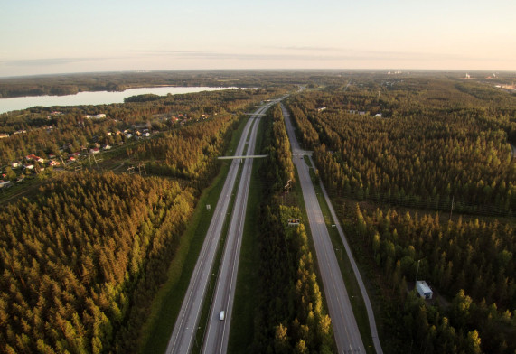 Valtatien molemmin puolin metsää, asuinaluetta ja järvet.