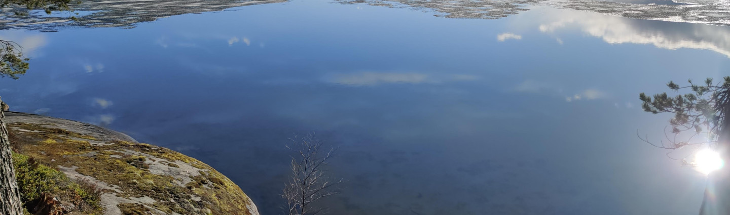 Viimeiset jäät sulamassa tyynen järven pinnasta auringonpaisteessa.