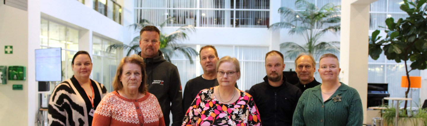 Ympäristölautakunnan kahdeksan jäsentä yhteiskuvassa kaupungintalon aulassa.