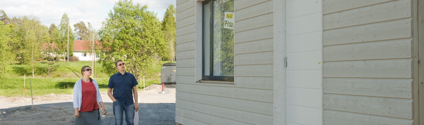 Pariskunta katselee keskeneräistä omakotitaloa.