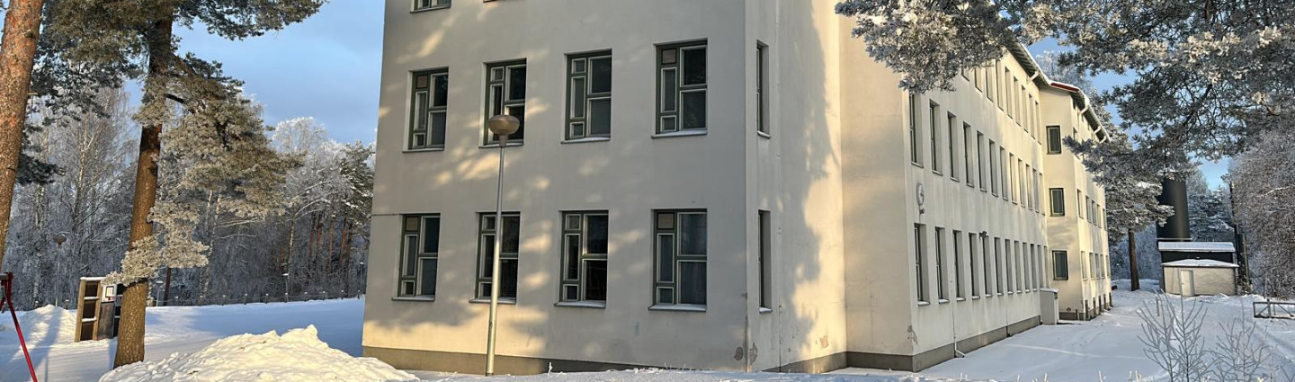 Kolmikerroksinen kivitalo lumisessa maisemassa.