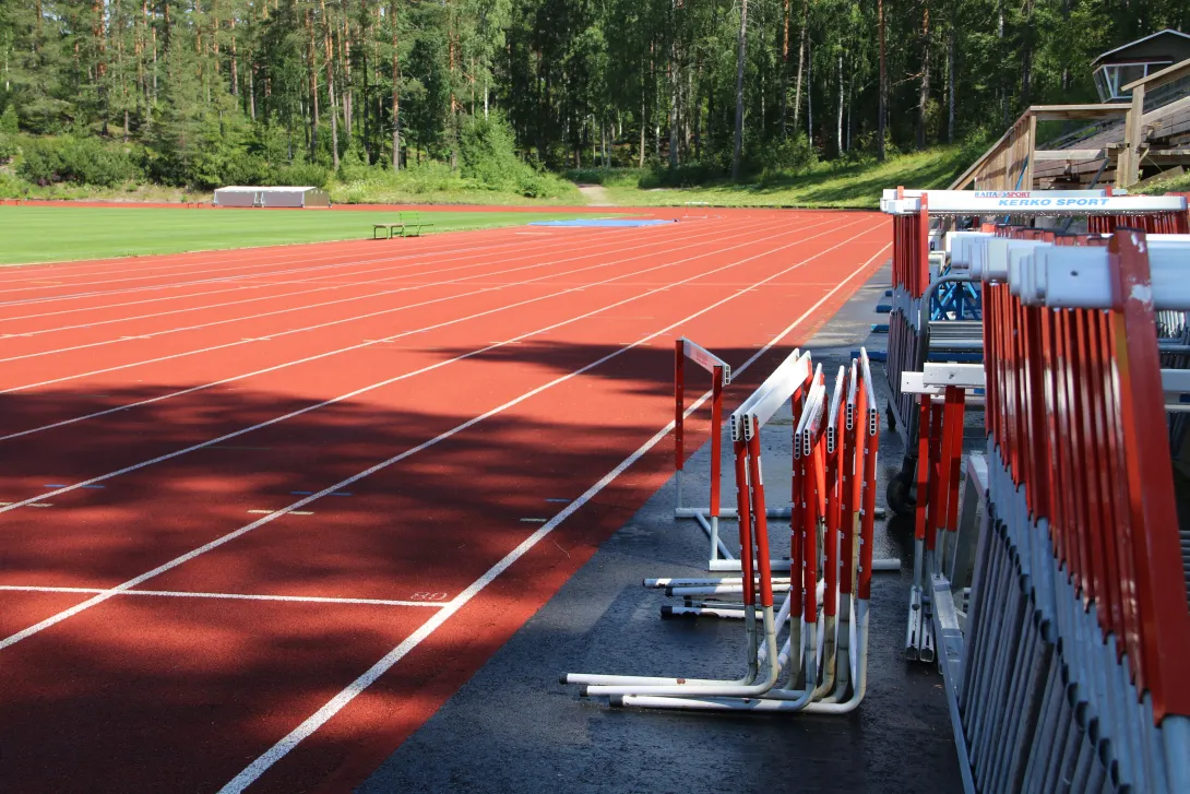 Ukonniemen urheilukentän juoksurata ja aidat rivissä kesällä.