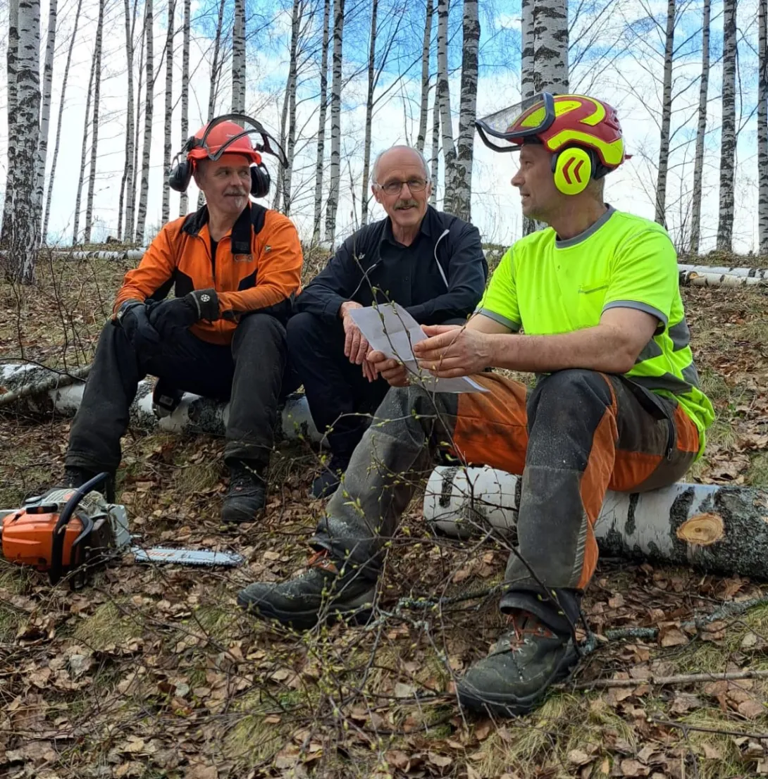 Ismo Tuomisto (vas.), Matti Luostarinen ja Seppo Knuuttila istuvat metsässä kesken savotan.