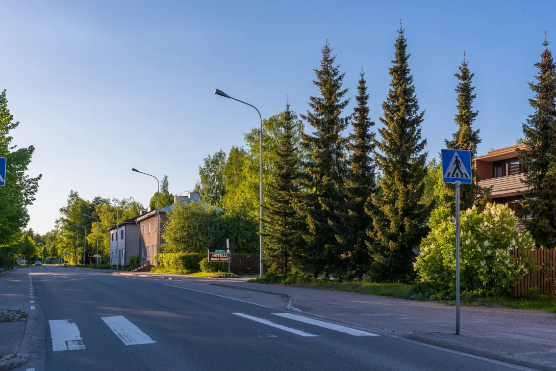 Kesäinen kuva, jossa etualalla suojatie ja taustalla pienkerrostaloja.