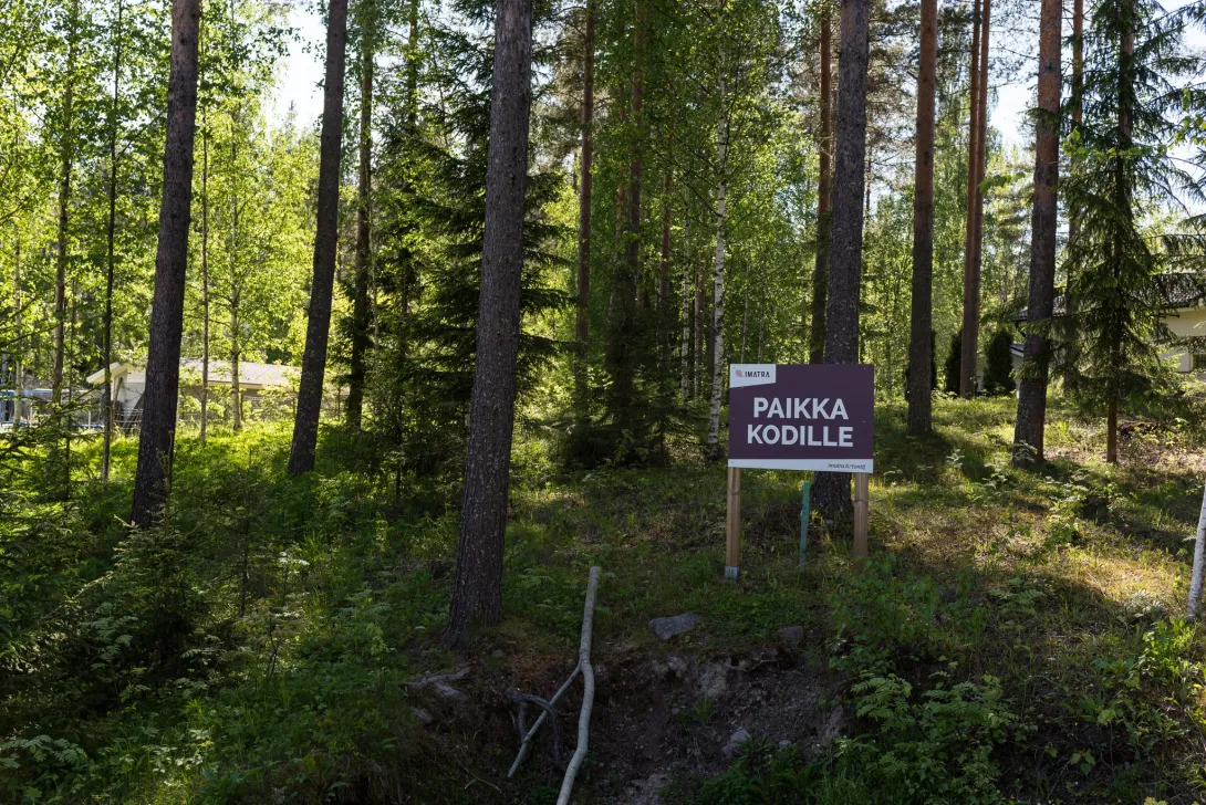 Paikka kodille -kyltti metsässä, tonttipaikalla.